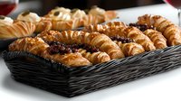 Fresh baked croissants filled with chocolate and jam arranged in black serving tray, close up view of flaky golden pastries for breakfast or cafe menu.