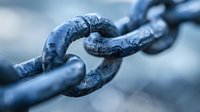 Macro view of weathered metal chain links in blue tones showing texture and connection details, symbolizing strength, unity and industrial concepts.