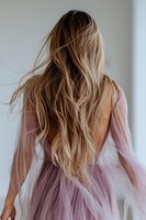 Young woman with flowing blonde hair wearing backless lavender tulle dress, photographed from behind in soft natural light. Hair styling and fashion concept.