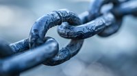 Weathered metal chain links in blue tones showing texture and connection detail, macro photography highlighting industrial strength and durability for business concepts.
