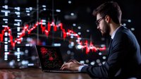 Caucasian businessman analyzing financial market crash on laptop with red stock chart falling in dark office, dramatic trading data visualization.