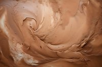 Swirling chocolate cream texture with smooth waves and ripples creating an abstract background pattern in rich brown and caramel tones.