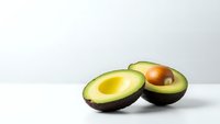 Fresh ripe avocado halves with pit on clean white background, healthy organic fruit for cooking, nutrition and diet concepts.