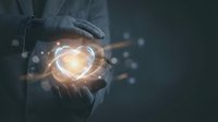 Businessman hands protecting glowing heart symbol with light effects representing care, love, health insurance and corporate social responsibility.