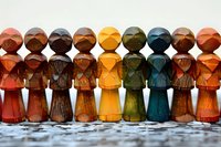 Colorful wooden peg dolls lined up in a row showing diversity and unity concept. Handcrafted folk art figures in earth tones create pattern of togetherness.