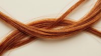 Copper wire strands twisted together in flowing curves against neutral background for electrical and industrial applications.