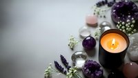 Spa wellness composition with burning candle, amethyst crystals, rose quartz stones and lavender flowers for relaxation and meditation rituals.