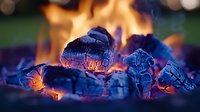 Glowing hot coals and burning wood embers in vibrant orange and blue colors create dramatic atmosphere for camping, grilling and outdoor cooking background.