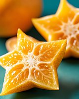 Star-shaped carambola slices showing juicy yellow flesh and distinctive ridged pattern against turquoise background, fresh tropical fruit for healthy eating.