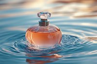 Round glass perfume bottle with pink fragrance floating on rippling blue water surface creating elegant splash and reflection in soft natural light.