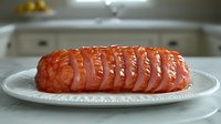 Fresh raw salmon fillet sliced into portions on white ceramic plate, ready for cooking, with natural lighting and soft focus background in kitchen setting.