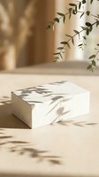 Minimalist white rectangular podium with natural leaf shadows cast across surface, neutral beige background with hanging eucalyptus branches, ideal for product display and branding mockups.