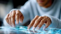 Elderly hands interacting with digital touchscreen interface showing glowing blue network connections, demonstrating senior technology adoption.