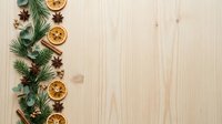 Festive holiday flat lay with dried citrus slices, evergreen branches, cinnamon sticks and star anise arranged on natural wood surface for seasonal decorating and holiday design projects.