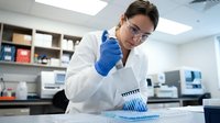 Asian male scientist in white lab coat using micropipette for precise liquid handling in modern research laboratory for medical testing and analysis.