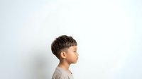 Young boy with short dark hair in profile view against white background, suitable for educational materials, child development content, and family-related designs.