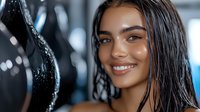 Young Hispanic woman with wet dark hair and glowing skin smiling confidently at camera. Natural makeup and white teeth create fresh, healthy appearance for wellness content.
