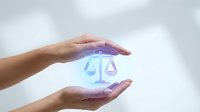 Protective hands surrounding glowing scales of justice symbol representing legal protection, law firm services, and balanced decision making in business.