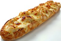 Freshly baked garlic bread topped with melted mozzarella cheese, golden brown and crispy on white baguette, close up view showing texture and grill marks.