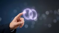 Hand holding glowing interlocked rings symbolizing partnership, connection and unity in business collaboration concept with bokeh background.