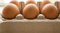 Fresh brown eggs in cardboard carton on wooden surface. Natural organic farm produce for cooking, baking and healthy breakfast meals.