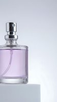 Elegant purple perfume bottle with silver spray nozzle on minimalist white surface against soft lavender background for luxury cosmetics branding.