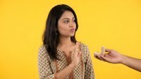 Young Indian woman refusing cigarette offer with hand gesture against bright yellow background promoting healthy lifestyle choices.