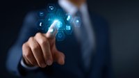 Businessman in dark suit touching virtual interface with glowing blue hexagonal icons, demonstrating digital transformation and future technology concept.