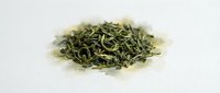 Dried green tea leaves isolated on white background, ready for beverage preparation, packaging design, and culinary use.