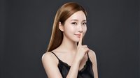 Young Asian woman making shush gesture with finger to lips, wearing black lingerie on dark background for beauty and fashion concepts.