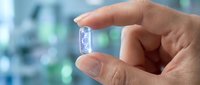 Hand holding transparent capsule pill with blurred medical background showing healthcare and pharmaceutical concept for wellness treatment.