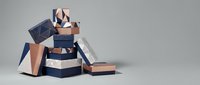 Stack of elegant gift boxes in navy blue, rose gold and copper tones with ribbons on neutral background for luxury shopping and celebration concepts.
