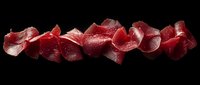 Fresh sliced prosciutto or cured ham arranged in artistic waves on dark background, showing delicate texture and marbling of premium meat cuts.