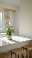 Modern minimalist kitchen interior with white countertop, wooden bar stools, potted plant with white flower, and natural light from window. Suitable for home design, interior decoration, and lifestyle publications.