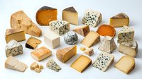 Assorted cheese varieties including cheddar, brie, blue cheese, and aged blocks isolated on white background for food photography, culinary design, restaurant menus, and dairy product marketing.