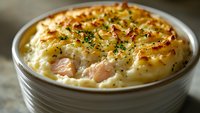Creamy fish pie with golden mashed potato topping and fresh herbs in ceramic dish. Comfort food casserole perfect for family dinners and recipe blogs.