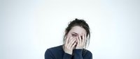 Young woman covering face with hands showing stress anxiety depression mental health struggle isolated on white background for wellness concepts.