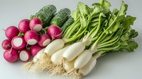 Fresh organic vegetables on light background - radishes with bright pink skin and white tips, green cucumbers, and white daikon radishes with leaves. Healthy food concept.