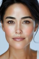 Close up portrait of Asian woman with natural makeup, glowing skin, and subtle smile against light background. Professional beauty and skincare concept.