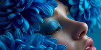 Young woman with closed eyes surrounded by vibrant blue feathers in dreamy artistic portrait for beauty and fashion concepts.