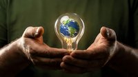 Hands protecting glowing light bulb with Earth inside representing environmental conservation and sustainable energy solutions for eco-friendly innovation.