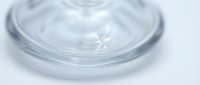Clear water droplet creating ripples on calm surface with soft lighting and minimal composition for wellness and purity concepts.