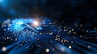 Glowing circuit board with bright light burst and bokeh effects in deep blue tones, representing digital technology, artificial intelligence and data processing.