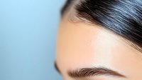 Close-up portrait of young woman with natural makeup and healthy glowing skin showing eyebrow and forehead area for beauty and skincare concepts.