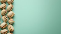 Pistachio nuts arranged on mint green background with copy space for food photography and healthy snacking concepts.