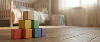 Colorful wooden toy blocks stacked on floor in bright nursery room with crib and soft natural lighting creating warm family atmosphere.