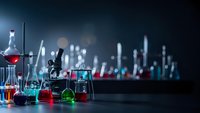 Laboratory glassware with colorful chemical solutions and microscope on dark background for scientific research and experimentation.