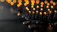 Black electric guitar headstock with golden tuning pegs against warm bokeh lights background creating musical atmosphere for concerts and performances.