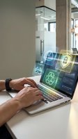 Man using laptop with digital security icons floating above screen, representing cybersecurity, data protection, and network safety in modern office environment for business technology concepts.