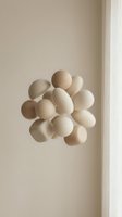 Cluster of cream-colored spheres arranged in organic formation against neutral beige wall with soft natural lighting, casting subtle shadows for minimalist design and contemporary interior styling.